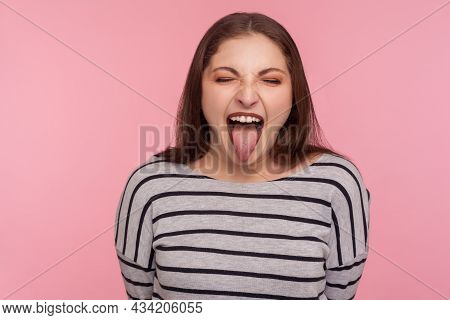 Portrait Of Disobedient Funny Woman In Striped Sweatshirt Showing Tongue Out, Expressing Displeasure