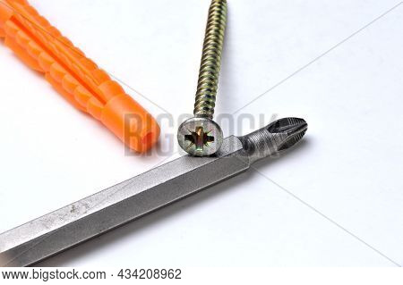 Plastic Dowel, Screwdriver And Several Screws On A Light Background. Close-up.