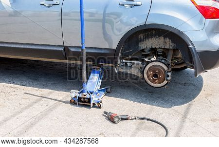 Car At The Tire Mounting With Removed Wheel On Pneumatic Jack. Seasonal Tire Change. Car Service Con