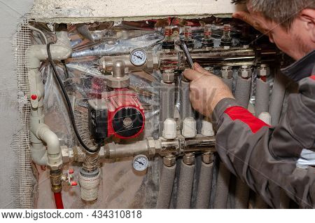 Repair And Service Concept Heating Systems. Specialist Inspects Floor Heating System. Adult Male Che