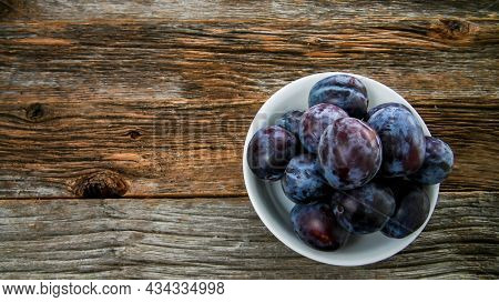 Italian plums on wooden background trop view