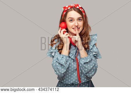 Shh, Keep Quiet. Pretty Pinup Girl Holding Phone Handset Looking At Camera, Asking For Silence Secre