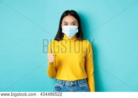 Covid-19, Social Distancing And Pandemic Concept. Young Woman In Medical Mask Showing Thumbs Up In A