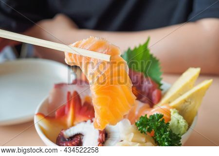 Salmon Slice In Chopsticks, Eating Sashimi Rice Bowl Chirashi Don Japanese Food