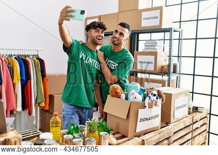 Young hispanic volunteers smiling happy making selfie by the smartphone at charity center.