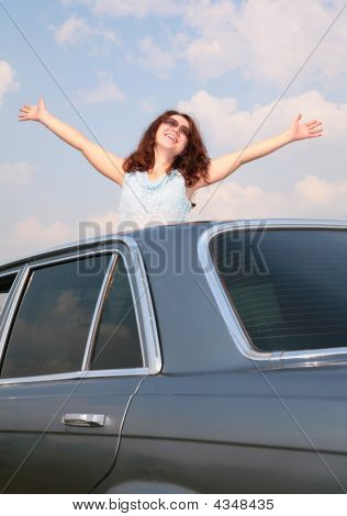Menina com as mãos levantadas e carro