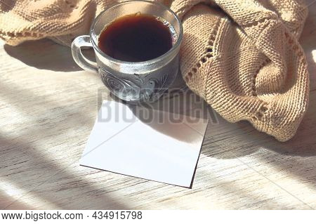 Cup Of Coffee And Empty Card For Message. Knitted Scarf On The Wooden Background. Flat Lay, Top View