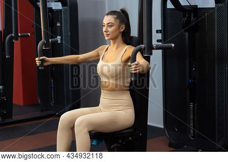 Fitness Woman Doing Exercises On The Shoulders On The Butterfly Simulator Machine