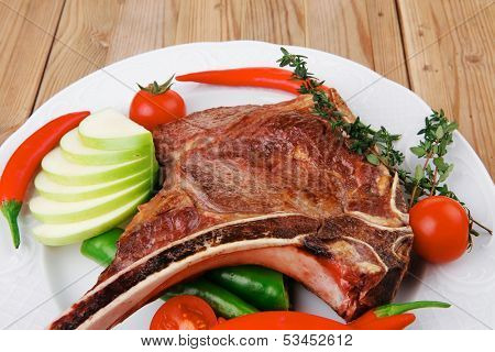 savory : roasted beef spare rib on white dish with cutlery thyme pepper and tomato on wooden table