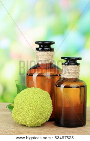 Osage Orange fruits (Maclura pomifera) and medicine bottles, on wooden table, on nature background