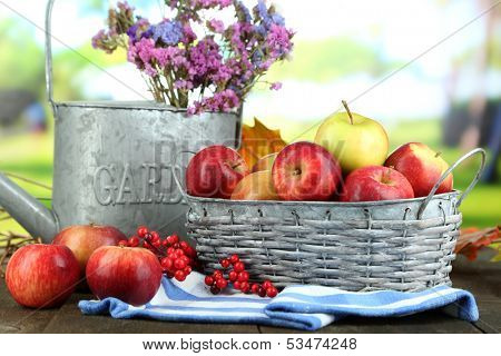 Juicy apples in basket on table on natural background