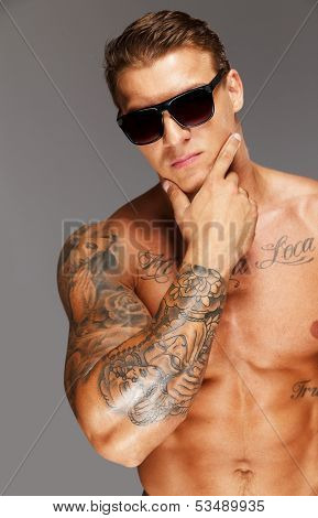 Handsome man in sunglasses with muscular tattooed torso