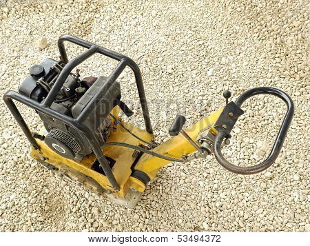 Old yellow plate compactor on aggregate bed