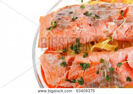 fresh fried natural pink salmon on italian traditional tagliatelle backed with tomato and vegetables isolated over white background