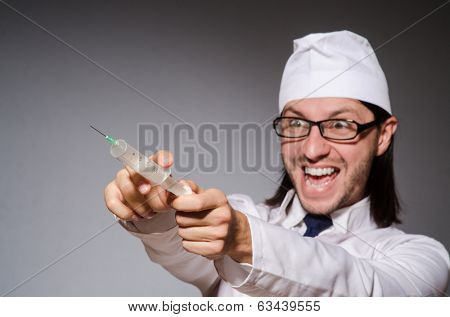 Young doctor man with  syringe against grey background