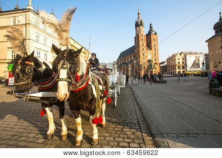 KRAKOW, POLAND - FEB 26, 2014: Carriages at Main Market Square. It dates to the 13th century, and at roughly 40,000 m it is the largest medieval town square in Europe.
