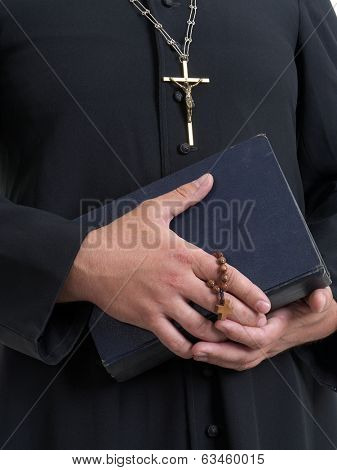 Closeup of catholic priest's hands holding the Holy Bible and rosary