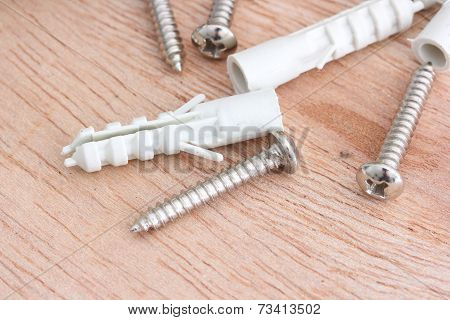 Screws And Plastic Anchor On The Wooden Background