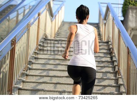 Runner athlete running on city stairs. woman fitness jogging workout wellness concept.