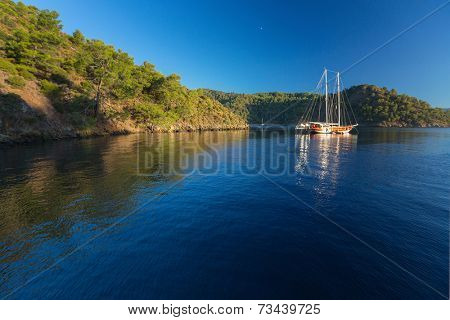 Calm bay with clear water and anchored sail boats. Turkey