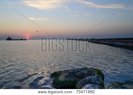 sunset at pier and a passing ship