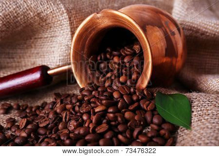 Coffee beans in ibrik on sacking background closeup