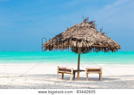 Two deck chairs and umbrella on tropical beach.