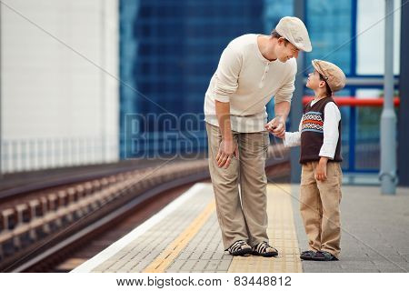 Young father and son on railway station platform