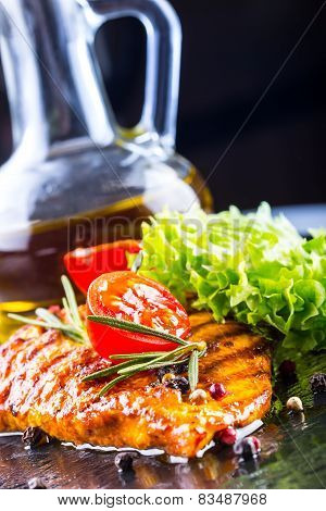 Steak chicken breast olive oil cherry tomatoes pepper and rosemary herbs.