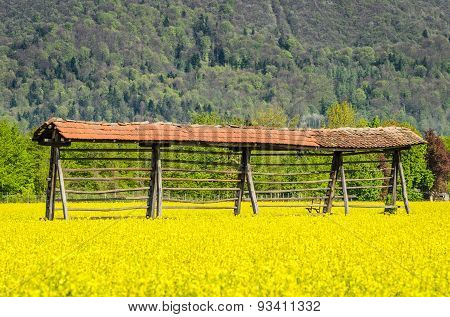 Hayrack Standing In A Field With Mountains In Background