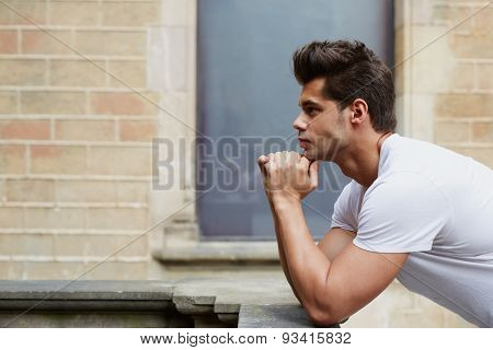 Side shot portrait of young handsome man thinking about something while standing outdoors