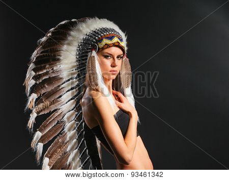 Beautiful woman in native american costume with feathers .
