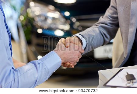 auto business, car sale, deal, gesture and people concept - close up of male handshake in auto show or salon