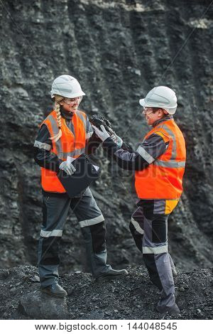 Two specialists examining coal at an open pit