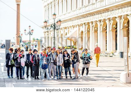 Venice, Italy - May 18, 2016: Group of asian tourists stand on San Marco square. Venice is very popular tourist destination among people from asia.