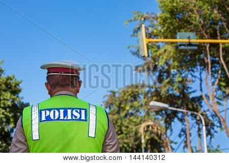 Indonesian police officer in fluorescent jacket standing on the street