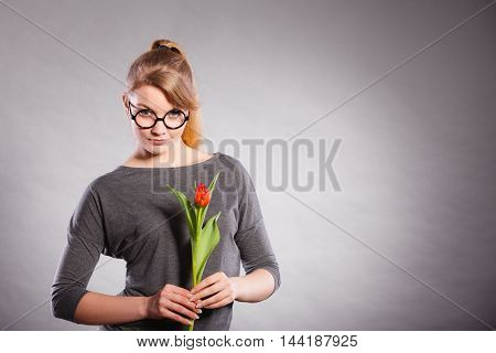 Delicacy and subtlety of women. Young adorable woman with spring flower. Portrait of beauty delicate girl in glasses with red beautiful tulip.