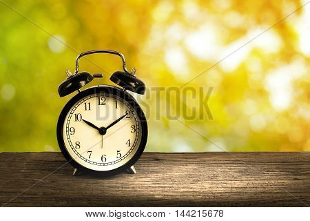 Alarm Clock On Wood With Blurry Shiny Bokeh In Background