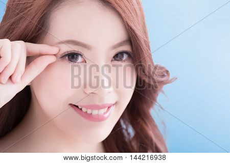 Woman face and eye care and she touch eye with hands asian beauty. Isolated over blue background asian beauty