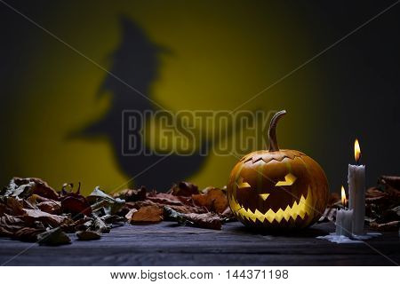 Pumpkin for Halloween, lamp of the pumpkin, witch silhouette, antique wood, celebrating halloween, smiley on a pumpkin, paraffin candles, burning candles, autumn dry leaves