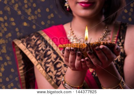 happy diwali greeting card showing indian beautiful Girl holding a diya on diwali festival, asian girl and diya, over black background