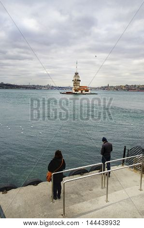 Istanbul Turkey - December 04 2013: European part of Istanbul in the background against the shore. Left Blue Mosque medium Hagia Sophia Topkapi palace dome seem right. The Maiden's Tower (Turkish: Kiz Kulesi) also known as Leander's Tower since the mediev