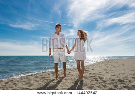 happy couple in love walking on the beach in summer white dress