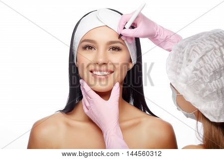 Young Woman before Plastic Surgery Operation Cosmetology. Doctor does line on a female face before plastic surgery. Beautician touching woman face. Beauty Face. Isolate on white background