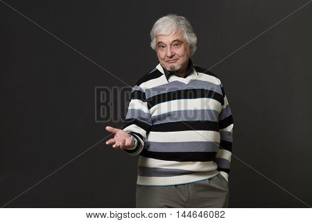 Portrait of handsome professor man of university or colleage showing his arm while explaining new theory, concept, prove in studio.
