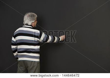 Picture of professor man of university or colleage whiting something on blackboard in studio. Teacher explaining new material to students or pupils.
