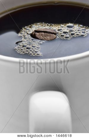 Kop kaffe med en bønne flyder i det