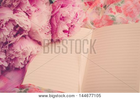 Pink peonies are on an open notebook. Blank pages (vintage)