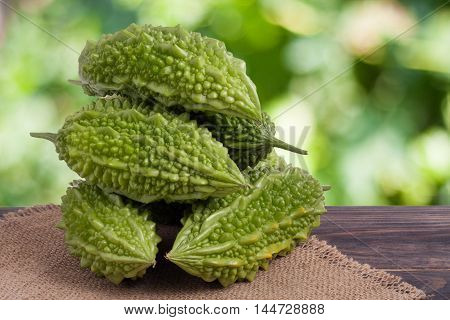 heap of bitter melon or momordica on wooden table with blurred background.