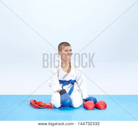 Cheerful athlete in karate pose near karate outfit